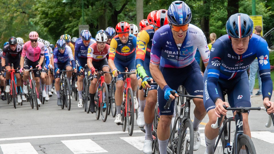 Un groupe d'une vingtaine de cyclistes dans une compétition. Ils roulent en direction de la caméra.