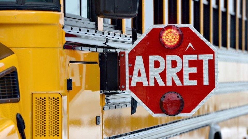 Un panneau d'arrêt d'un autobus scolaire est déplié et clignote.