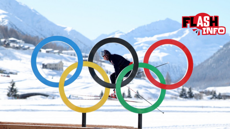 Un skieur montre ses talents derrière des anneaux olympiques géants.