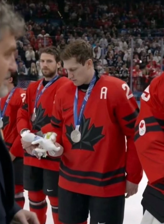 Lors de la remise des médailles olympiques, on voit un hockeyeur canadien regarder la peluche qu'il vient de recevoir.