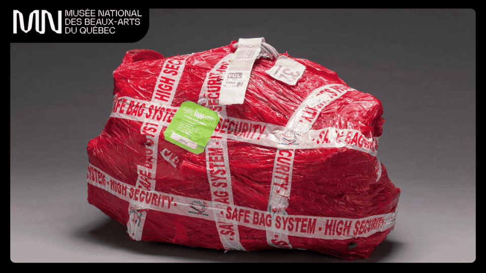 Un paquet d’une forme irrégulière, emballée dans du cellophane rouge et de l’adhésif sur lequel il est écrit: safe bag system high security