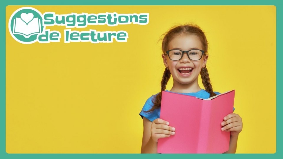 Une fillette à lunettes qui rit et tient un livre rose dans ses mains