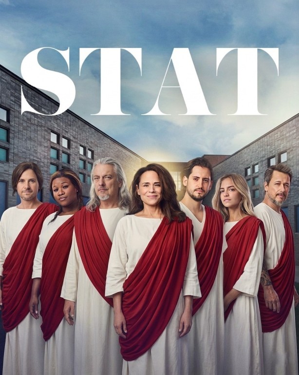 On voit les personnages de la série Stat, qui sont normalement des médecins. Cette fois-ci, ils sont habillés en Jésus. C'est-à-dire qu'il portent une sorte de drap blanc, avec une sorte de drap rouge qui va en diagonale, de leur épaule à leur hanche. 