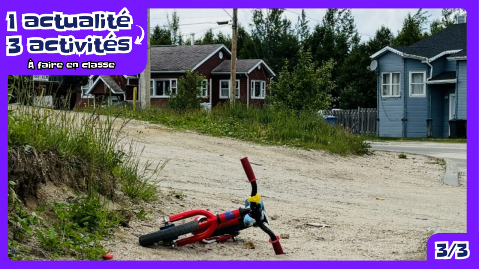 Au premier plan, un très petit vélo rouge abandonné dans une allée en sable. En arrière plan, deux maisons. 